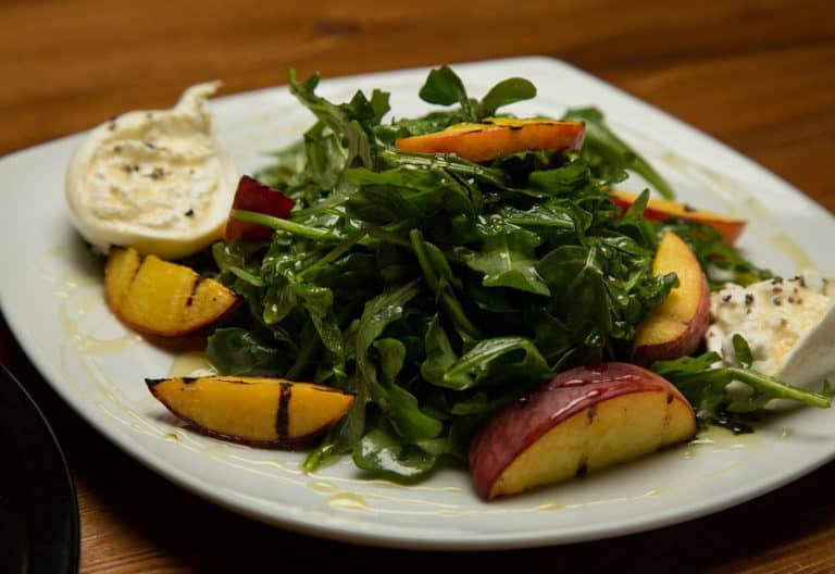 Fresh arugula salad with peaches and goat cheese